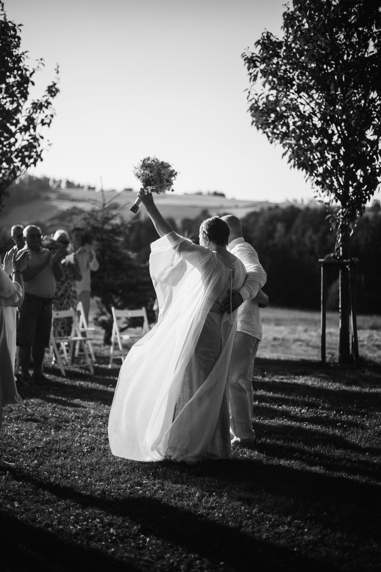Nevěsta zvedá svatební kytici, černobílá fotografie z obřadu